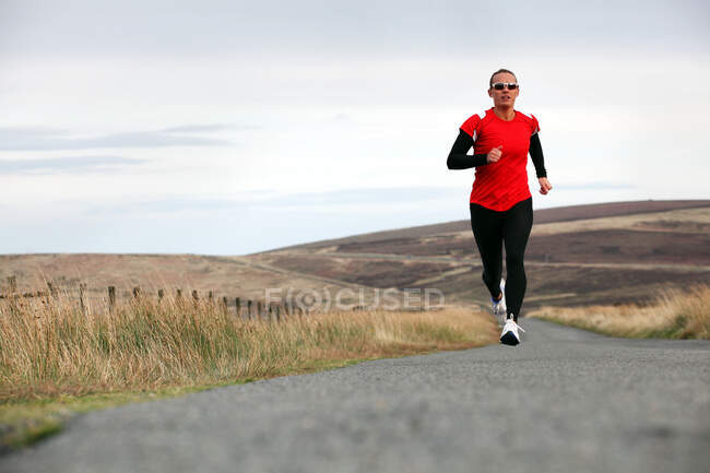 Triathlete running on rural road — Stock Photo