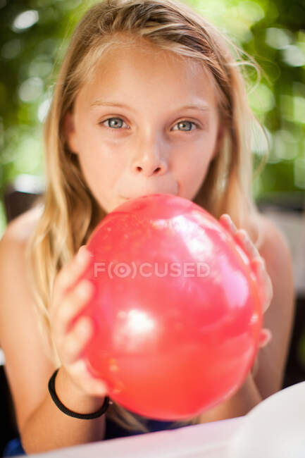 Girl blowing up balloon at party — Stock Photo