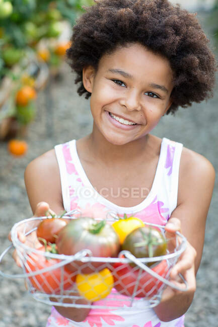 Mädchen hält Korb mit reifen Tomaten — Stockfoto