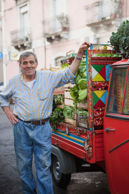 Fruit vendor next to his ape-transporter — Stock Photo