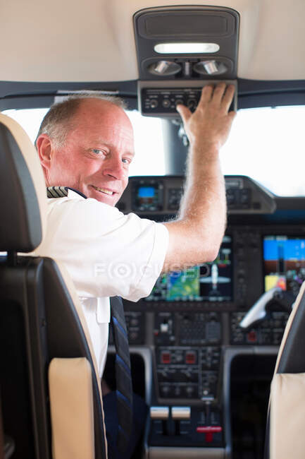 Piloto sonriendo en cabina de avión - foto de stock