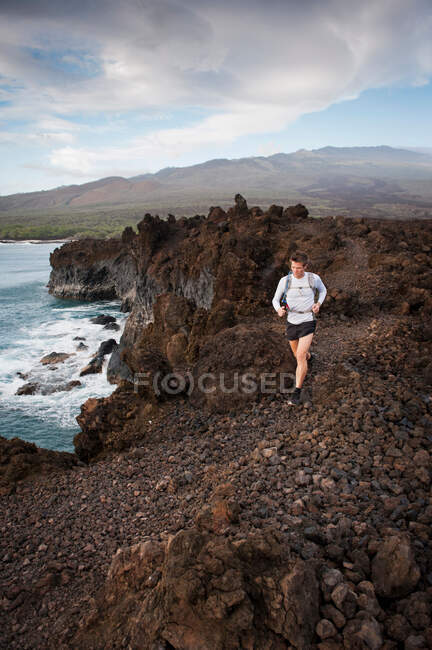 Hombre corriendo por sendero rural rocoso - foto de stock