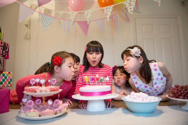 Girls blowing out birthday candles on cake — Stock Photo