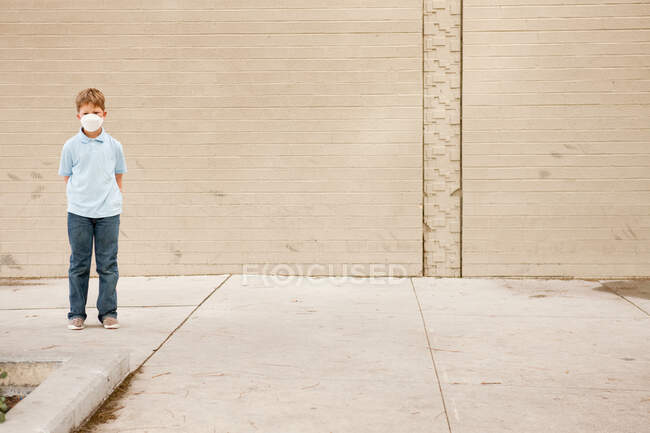 Giovane ragazzo in piedi da muro di mattoni indossando maschera antipolvere — Foto stock