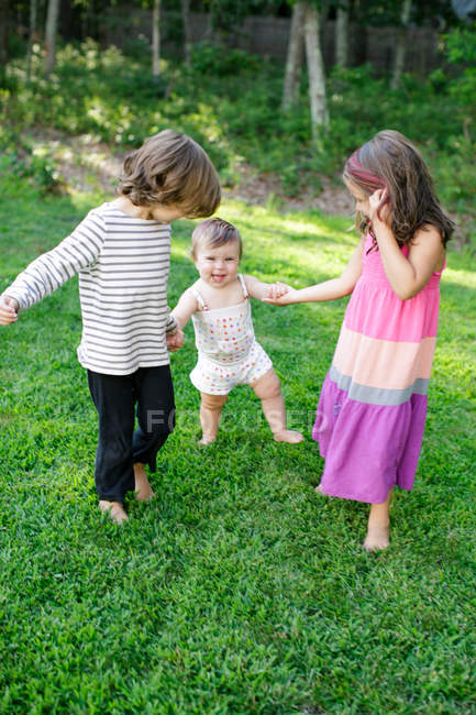 Female toddler with boy and girl in garden — Stock Photo