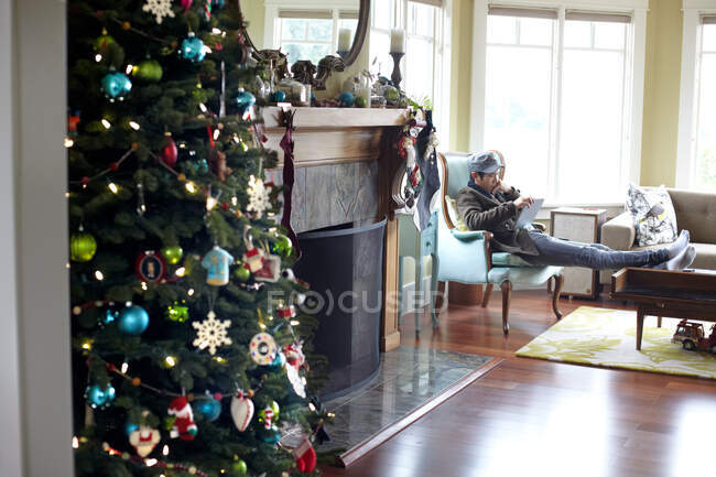 Man using digital tablet in room with christmas tree — Stock Photo