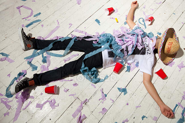 Мужчина, лежащий на полу, покрытый лентами на вечеринке — стоковое фото