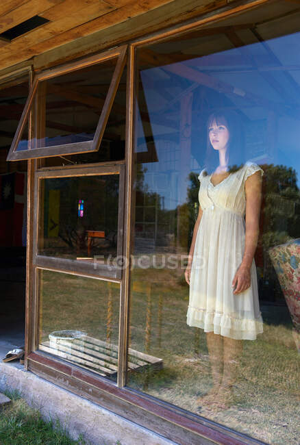 Teenage girl standing in window — Stock Photo