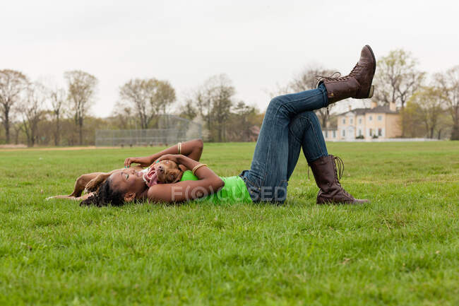 Mujer joven y su perro jugando en la hierba - foto de stock