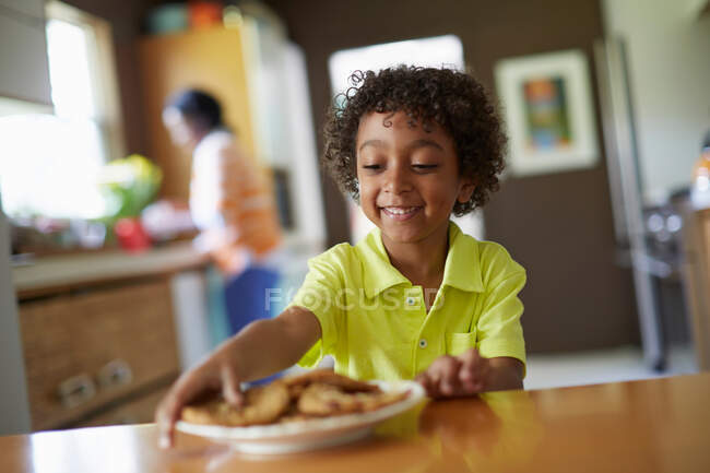 Junge blickt auf Teller mit Keksen — Stockfoto