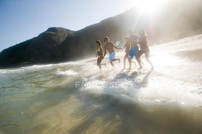Teenagers running into the sea — Stock Photo