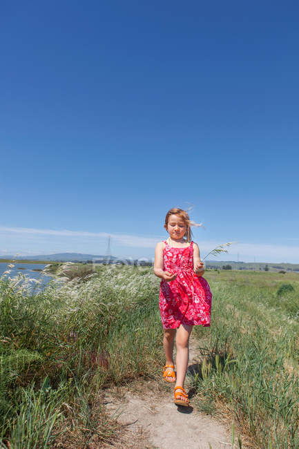 Girl walking by river marsh — Stock Photo
