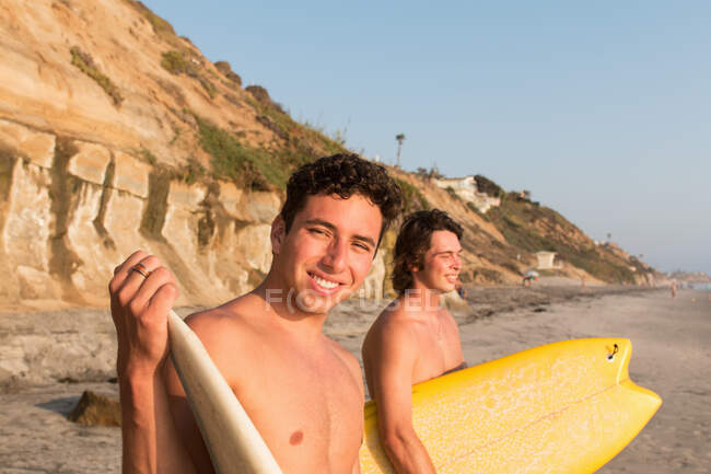 Two young men on beach, holding surfboards — Stock Photo