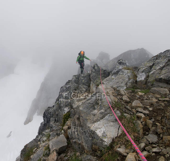 Mulher alpinista cruzando cume de rocha, Picket Pass, North Cascades National Park, WA, EUA — Fotografia de Stock