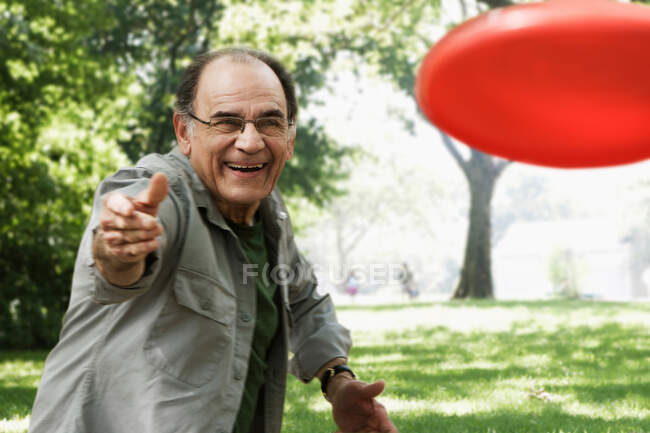 Senior wirft rote Fliegerscheibe — Stockfoto
