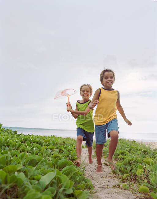 Crianças correndo juntas na praia — Fotografia de Stock