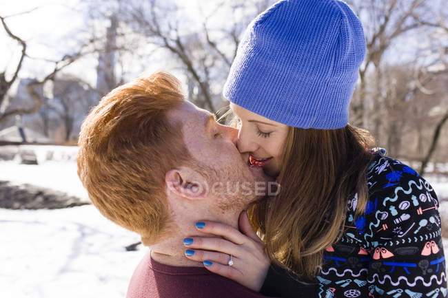 Romántica pareja joven besándose en el nevado Central Park, Nueva York, Estados Unidos - foto de stock