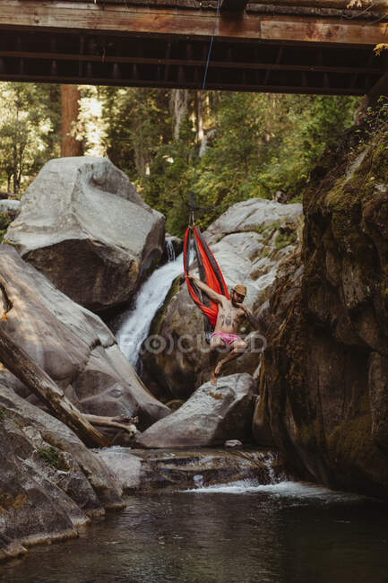 Young man jumping from hammock, suspended from bridge, Mineral King, Sequoia National Park, California, USA — Stock Photo