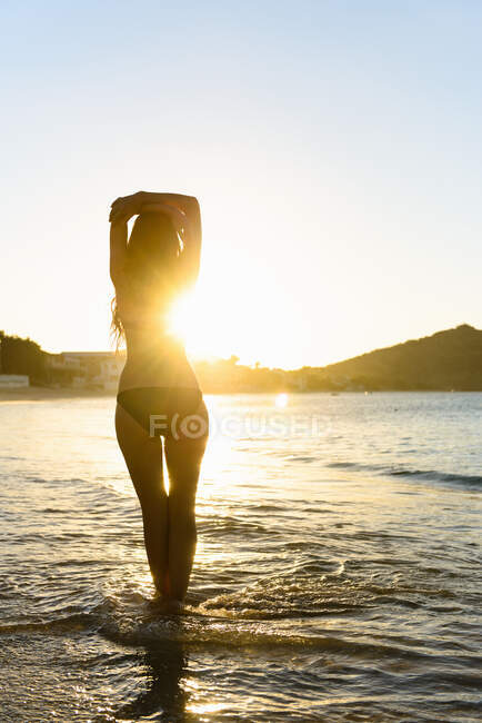 Femme marchant dans les vagues sur la plage — Photo de stock