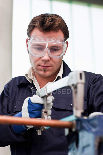 Plumber cutting copper pipe in workshop — Stock Photo