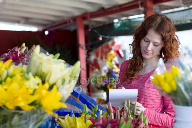 Florist making notes in shop — Stock Photo