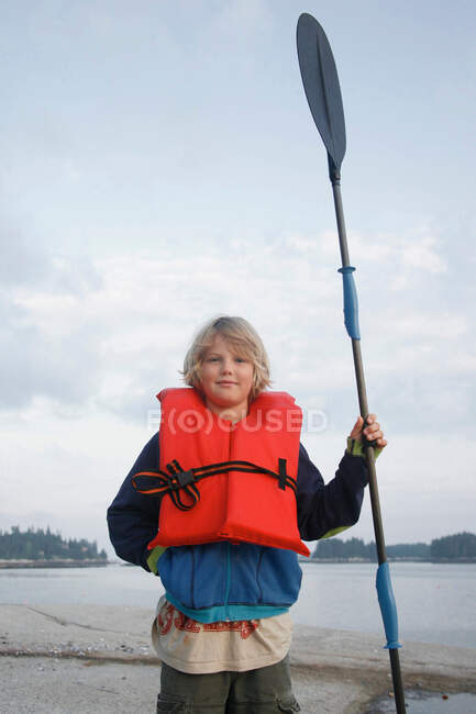 Ragazzo con giubbotto salvagente e pagaia in kayak — Foto stock