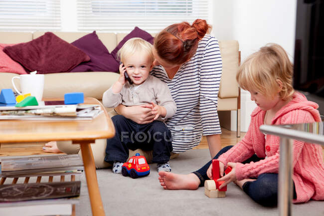 Madre che gioca con i bambini, ragazzo sul cellulare — Foto stock