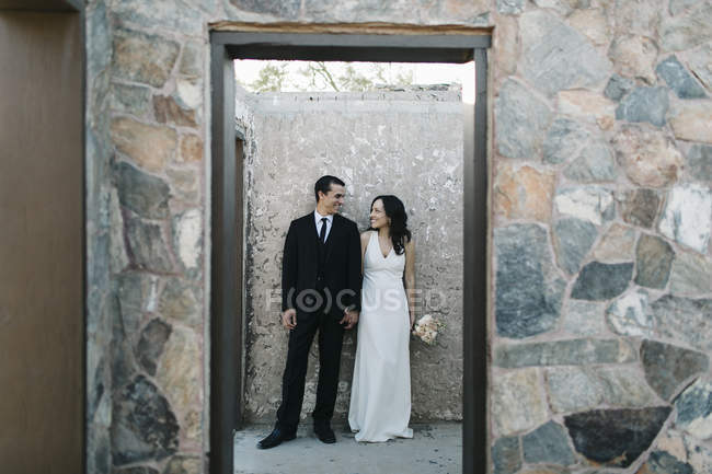 Жених и невеста, на улице, держатся за руки, улыбаются — стоковое фото