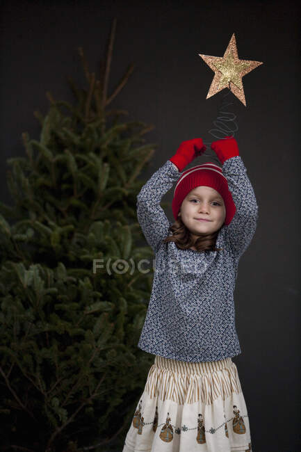 Retrato de una niña sosteniendo una decoración navideña - foto de stock