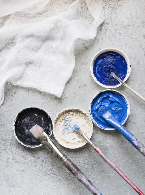 High angle view of paintbrushes and fresh paints on rustic surface — Stock Photo