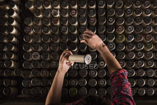 Hands of male lace weaver replacing threads on old weaving machine in textile mill — Stock Photo