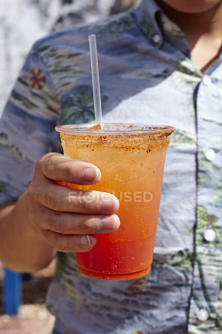 Young man holding michelada cocktail, mid section, close-up — Stock Photo