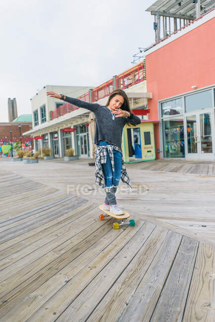 Girl skateboarding on boardwalk — Stock Photo