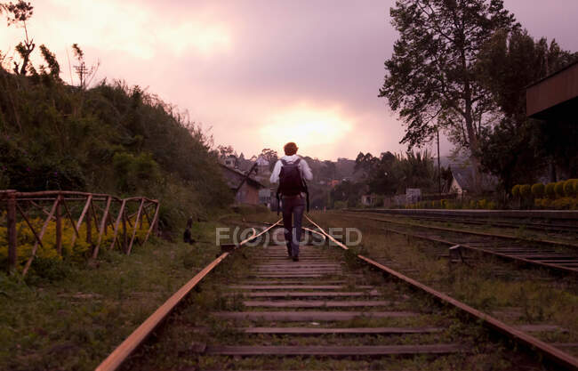 Homem mochila em trilhos de trem — Fotografia de Stock