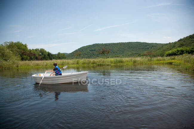 Boy manoeuvring boat in lake — Stock Photo