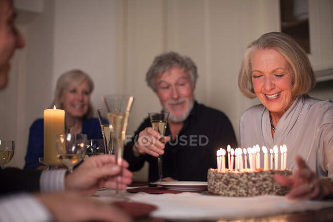 Donna anziana e amici con torta di compleanno — Foto stock