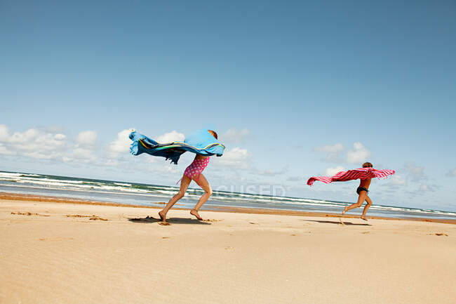 Meninas correndo com cobertores na praia — Fotografia de Stock