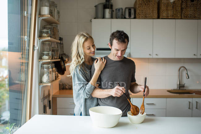 Couple mixing salad bowl in kitchen — Stock Photo