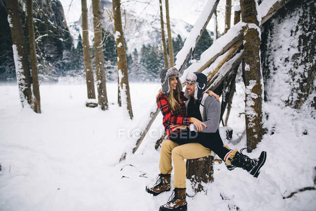 Mujer sentada sobre el hombre en un paisaje cubierto de nieve - foto de stock