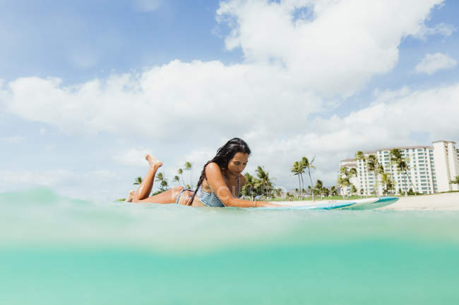 Surface level view of woman lying on surfboard, Oahu, Hawaii, USA — Stock Photo