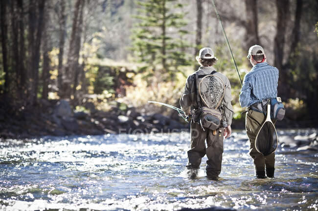 Fishermen ankle deep in river fly fishing, Colorado, USA — Stock Photo