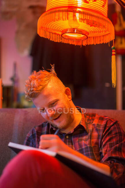 Hombre dibujando bajo lámpara naranja - foto de stock