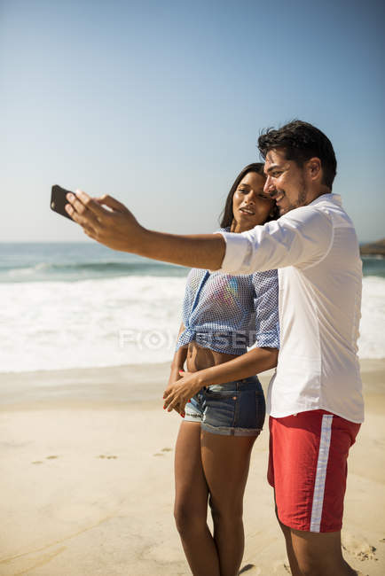 Couple taking self portrait on smartphone, Arpoador beach, Rio De Janeiro, Brazil — Stock Photo
