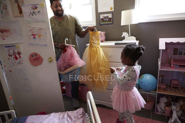 Отец помогает дочери выбрать одежду для вечеринки — стоковое фото