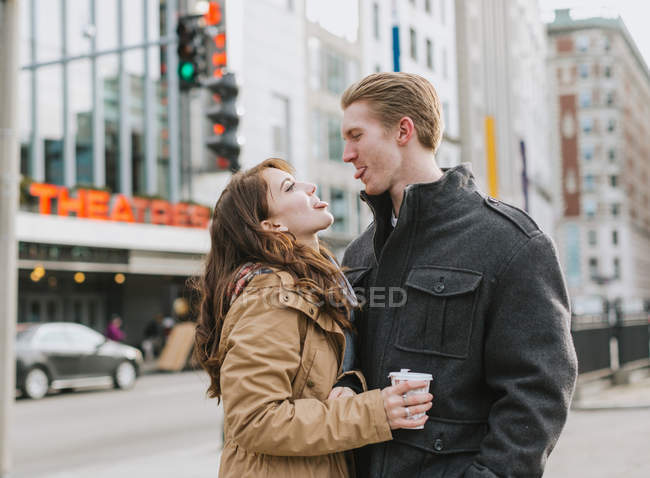 Молода пара стоїть на вулиці, обличчям до обличчя, стирчить язиками — стокове фото
