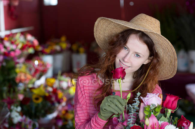 Floristería oliendo flores en la tienda - foto de stock