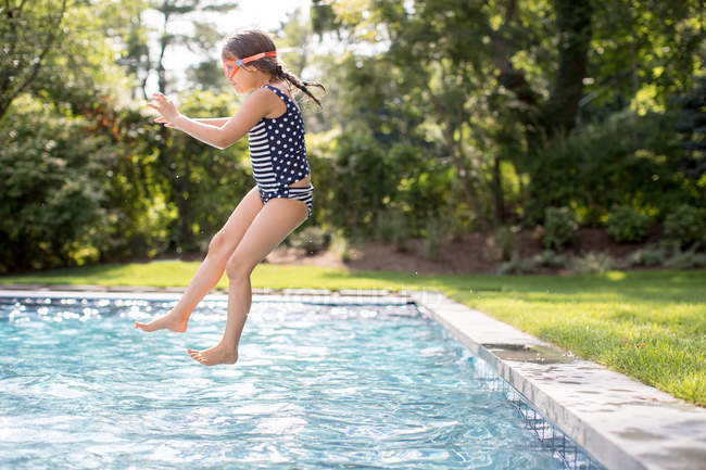 Girl jumping into outdoor swimming pool — Stock Photo