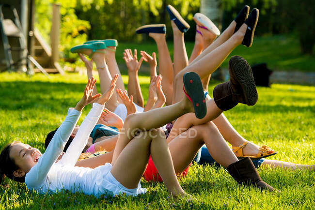Дівчата лежать на траві з піднятими руками і ногами — стокове фото