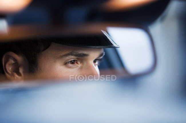 Chauffeur reflected in rear view mirror — Stock Photo