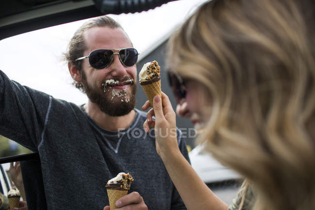 Junges Paar neben Jeep isst messisch Eistüten — Stockfoto